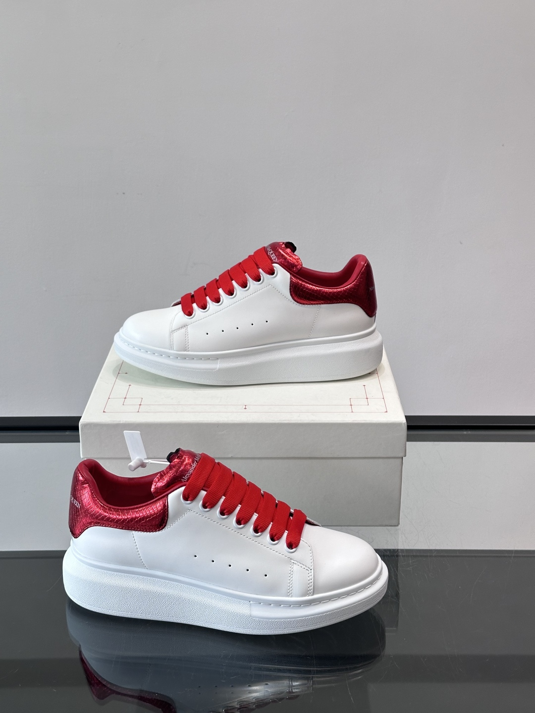 Alexander McQueen 红尾小白鞋采用白色牛皮革鞋面+红色蛇皮纹理后跟，搭配同色鞋带，视觉超