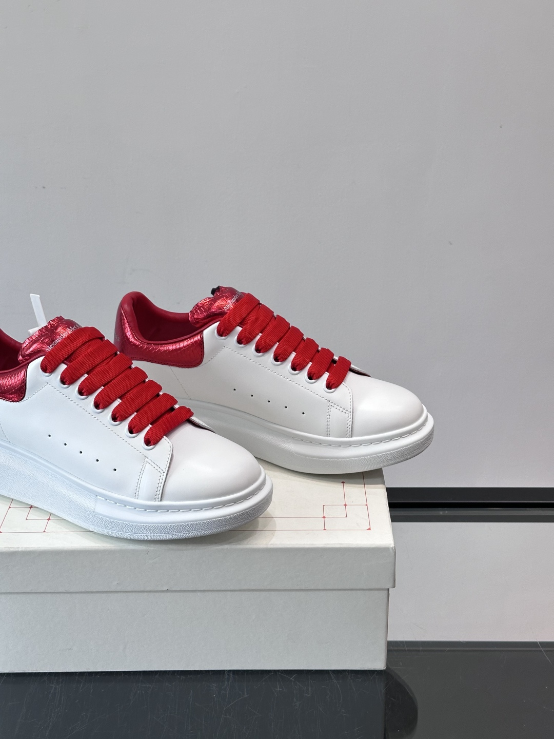 Alexander McQueen 红尾小白鞋采用白色牛皮革鞋面+红色蛇皮纹理后跟，搭配同色鞋带，视觉超