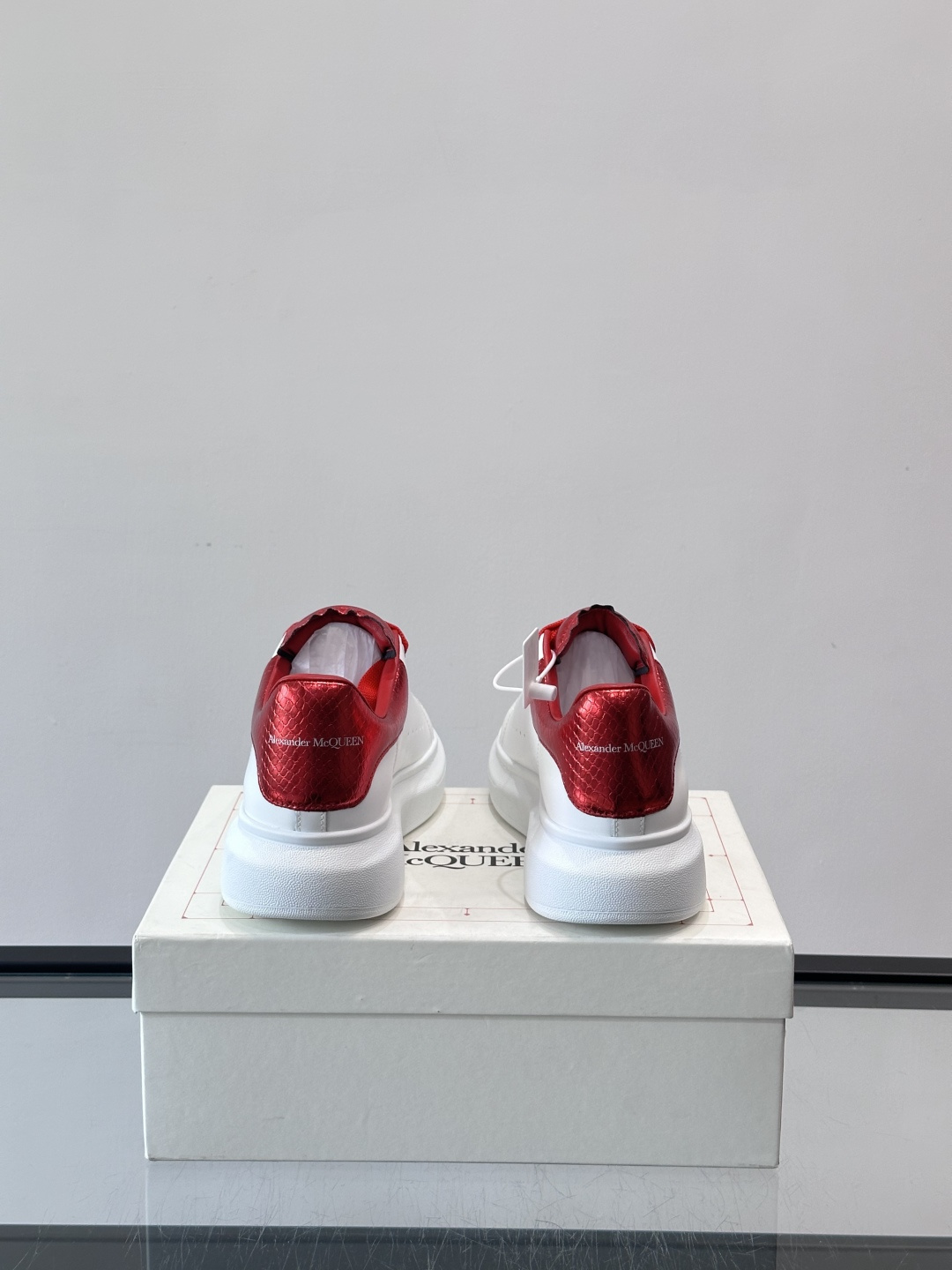 Alexander McQueen 红尾小白鞋采用白色牛皮革鞋面+红色蛇皮纹理后跟，搭配同色鞋带，视觉超