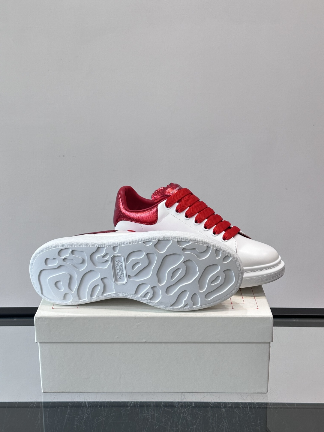 Alexander McQueen 红尾小白鞋采用白色牛皮革鞋面+红色蛇皮纹理后跟，搭配同色鞋带，视觉超