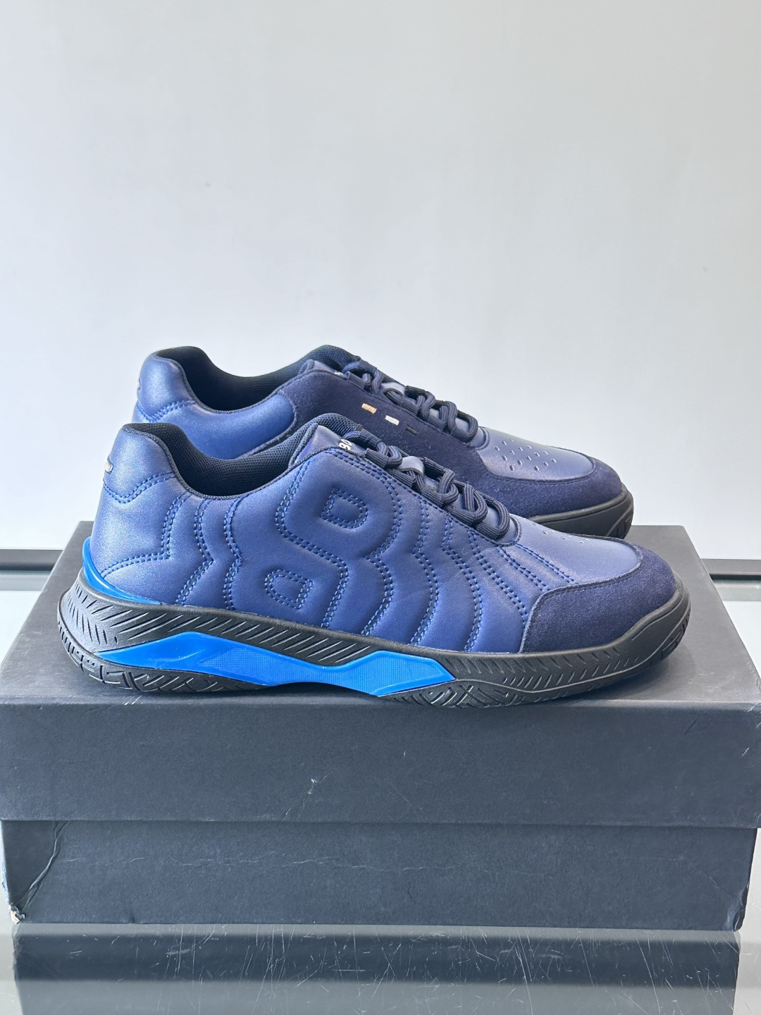 Boss Courtstride系列休闲鞋，灵感来自网球鞋，鞋面采用牛皮+绒面革拼接，绗缝工艺+双B标志