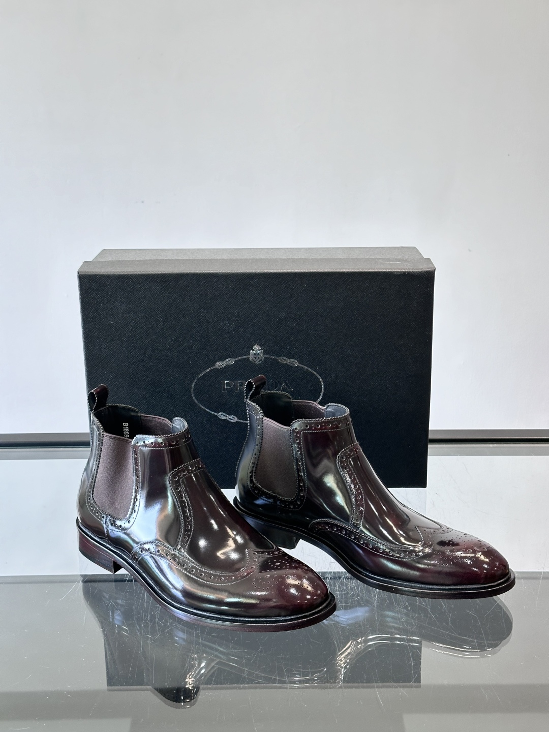 Prada普拉达布洛克雕花切尔西靴，英伦风代表，采用高光抛光皮革，光泽感如黑曜石。鞋面布洛克雕花，细节精
