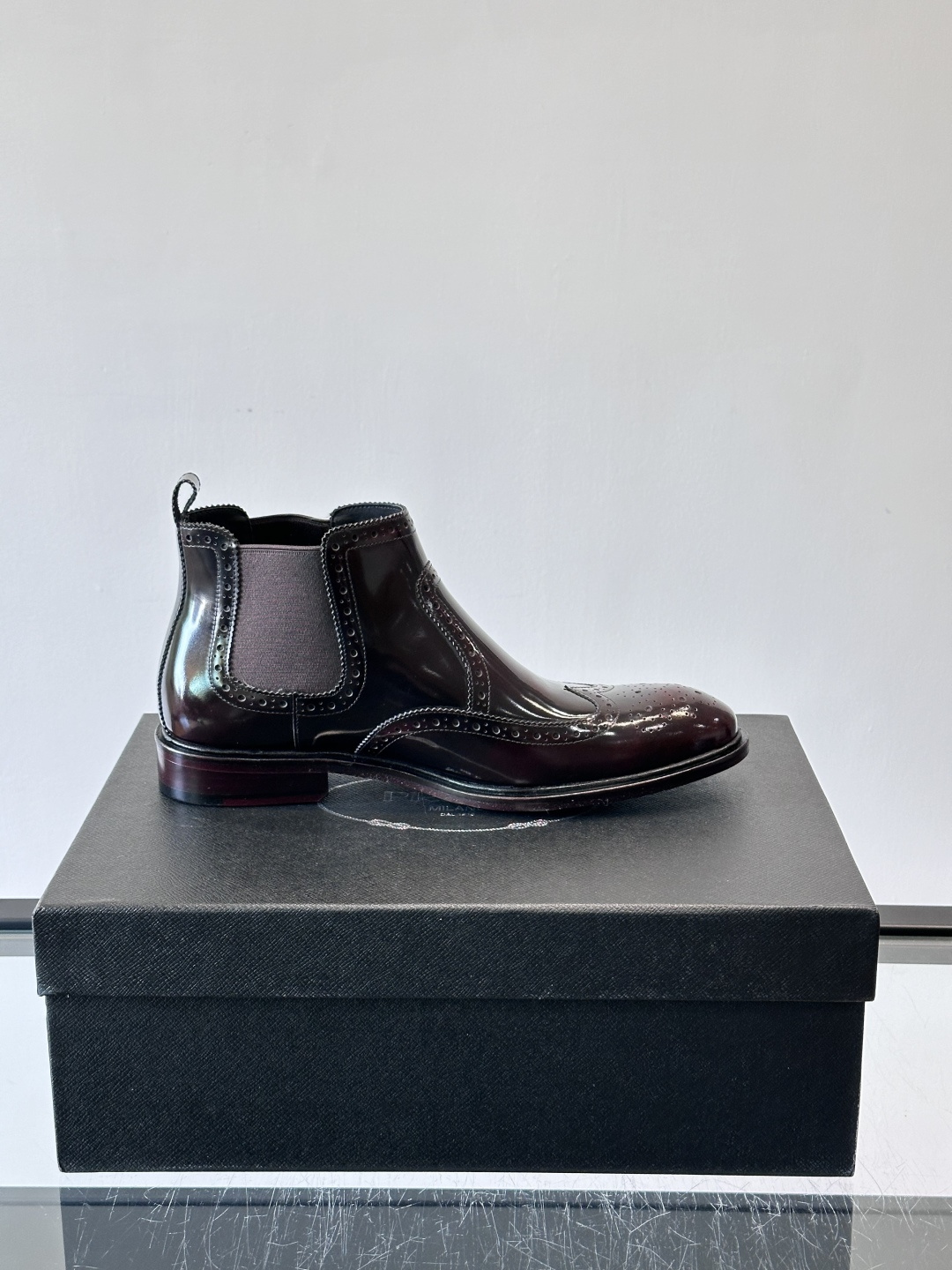 Prada普拉达布洛克雕花切尔西靴，英伦风代表，采用高光抛光皮革，光泽感如黑曜石。鞋面布洛克雕花，细节精