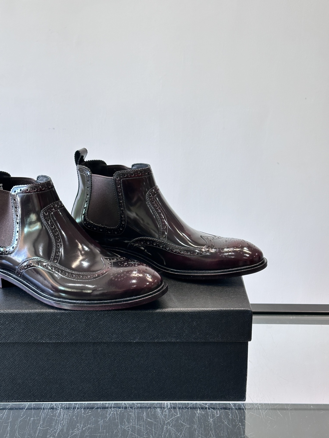 Prada普拉达布洛克雕花切尔西靴，英伦风代表，采用高光抛光皮革，光泽感如黑曜石。鞋面布洛克雕花，细节精