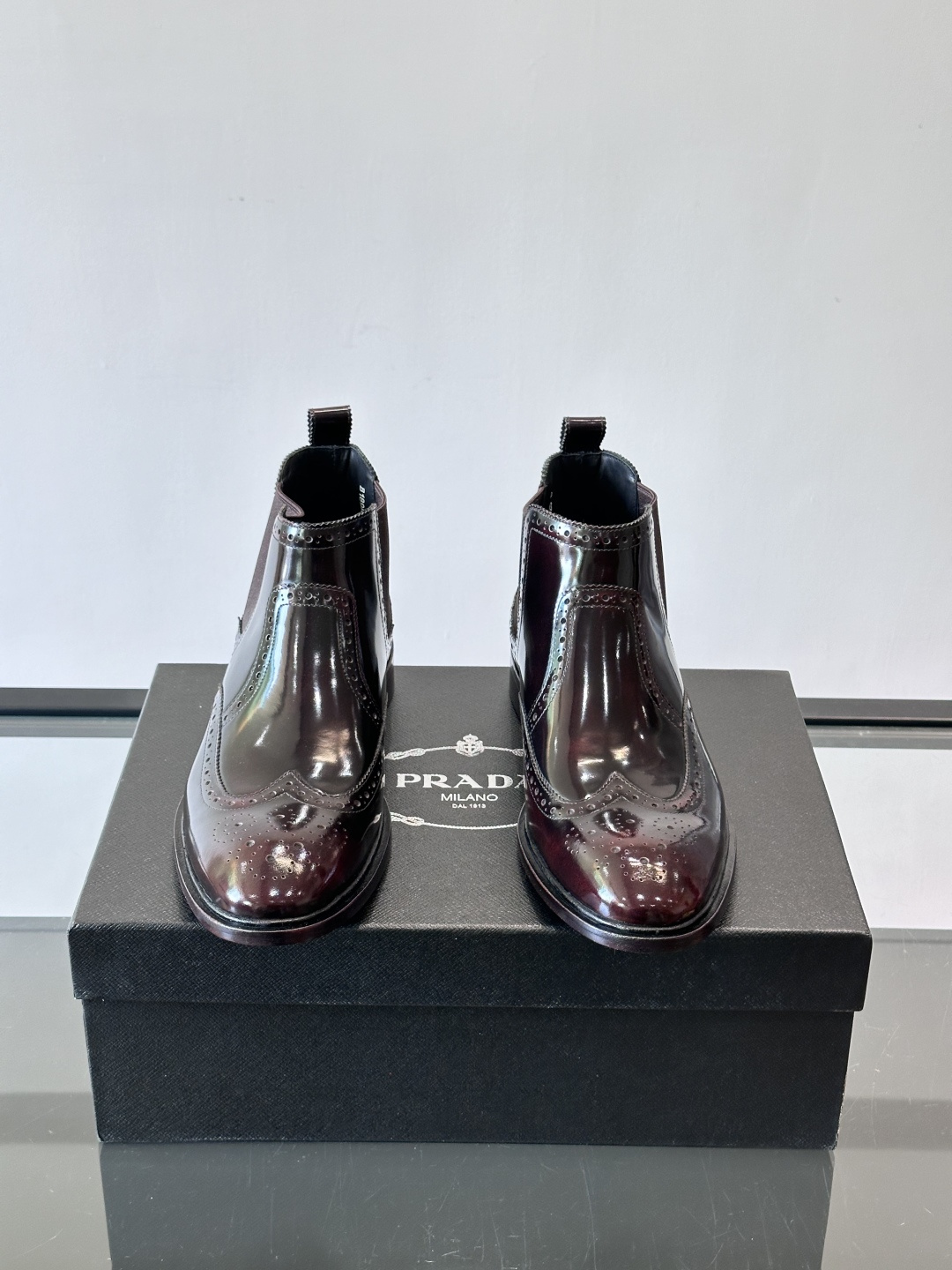 Prada普拉达布洛克雕花切尔西靴，英伦风代表，采用高光抛光皮革，光泽感如黑曜石。鞋面布洛克雕花，细节精