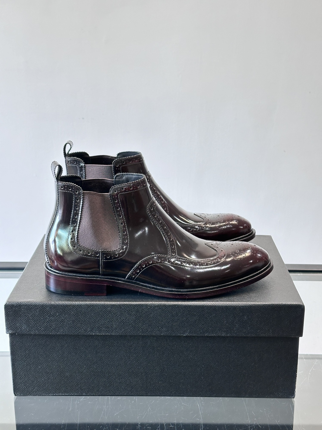 Prada普拉达布洛克雕花切尔西靴，英伦风代表，采用高光抛光皮革，光泽感如黑曜石。鞋面布洛克雕花，细节精