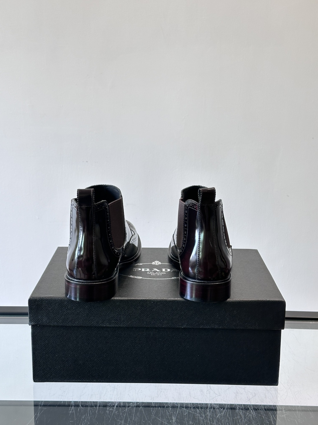 Prada普拉达布洛克雕花切尔西靴，英伦风代表，采用高光抛光皮革，光泽感如黑曜石。鞋面布洛克雕花，细节精
