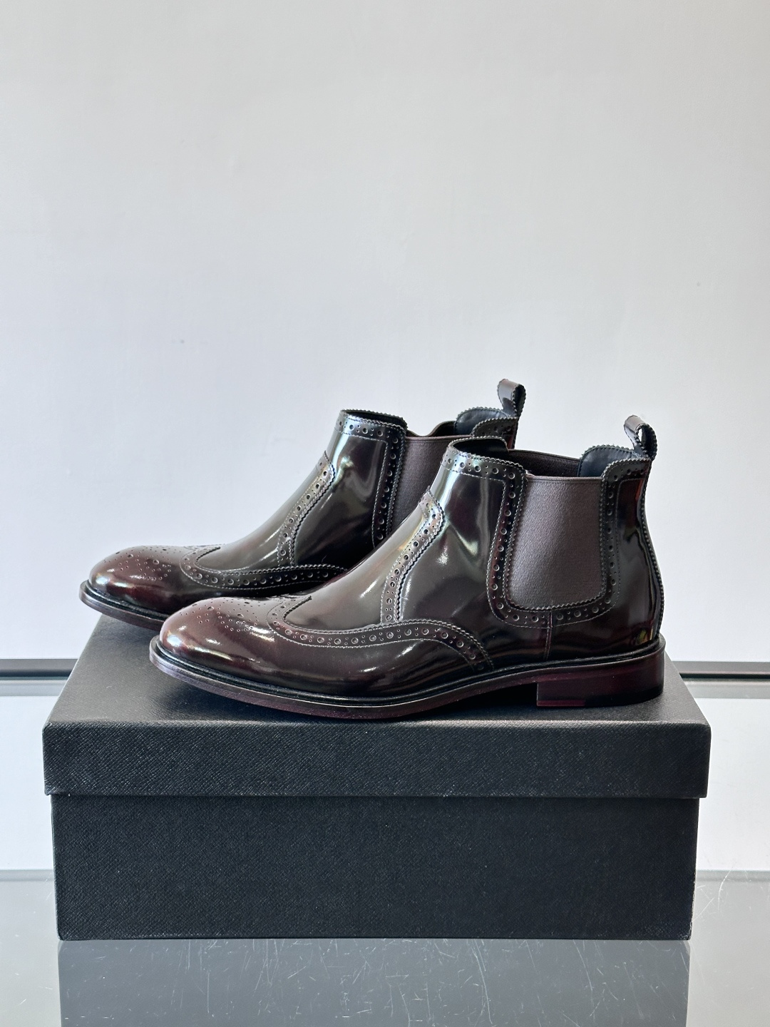 Prada普拉达布洛克雕花切尔西靴，英伦风代表，采用高光抛光皮革，光泽感如黑曜石。鞋面布洛克雕花，细节精