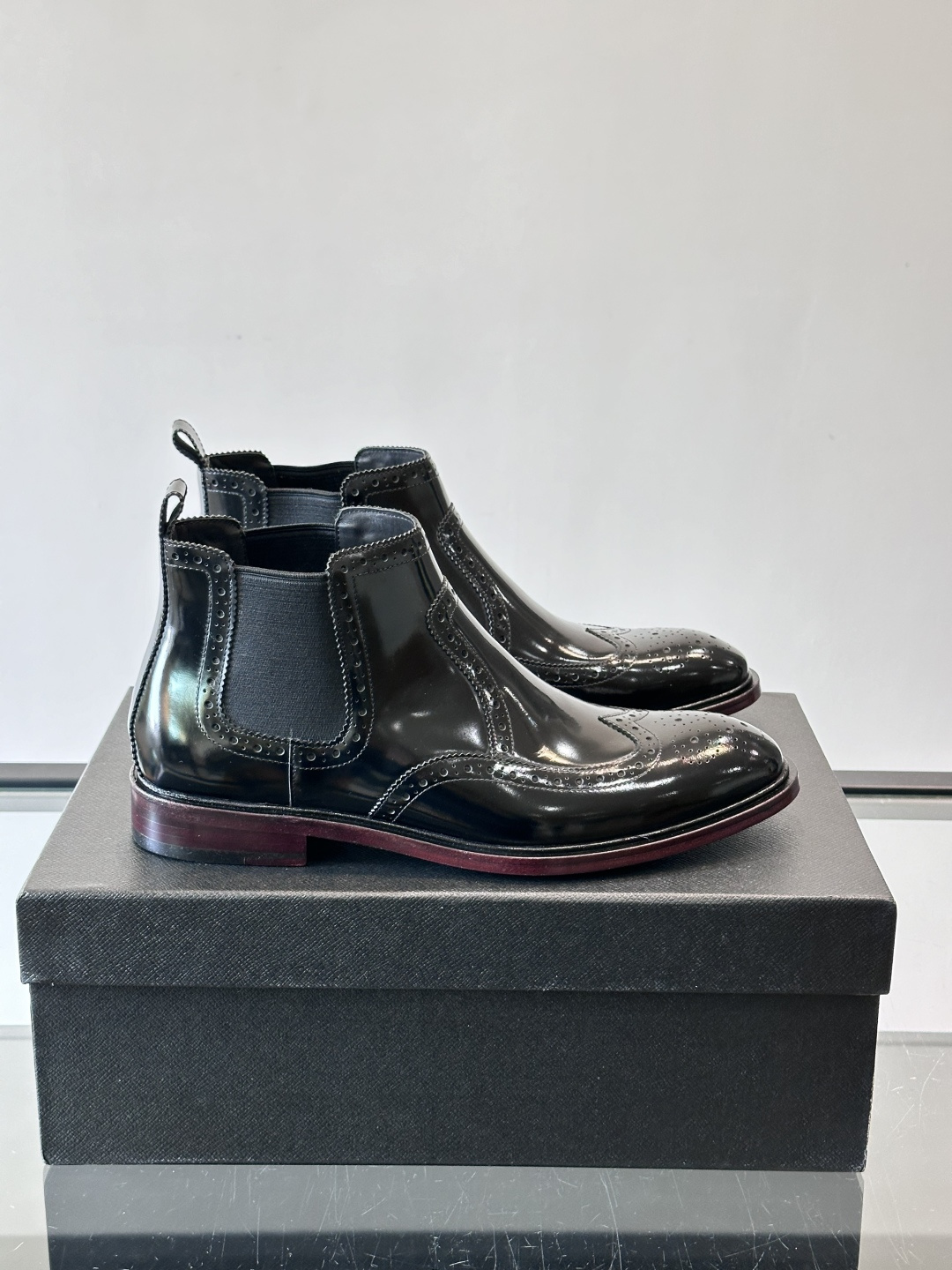 Prada普拉达布洛克雕花切尔西靴，英伦风代表，采用高光抛光皮革，光泽感如黑曜石。鞋面布洛克雕花，细节精