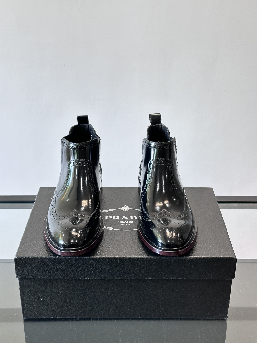 Prada普拉达布洛克雕花切尔西靴，英伦风代表，采用高光抛光皮革，光泽感如黑曜石。鞋面布洛克雕花，细节精