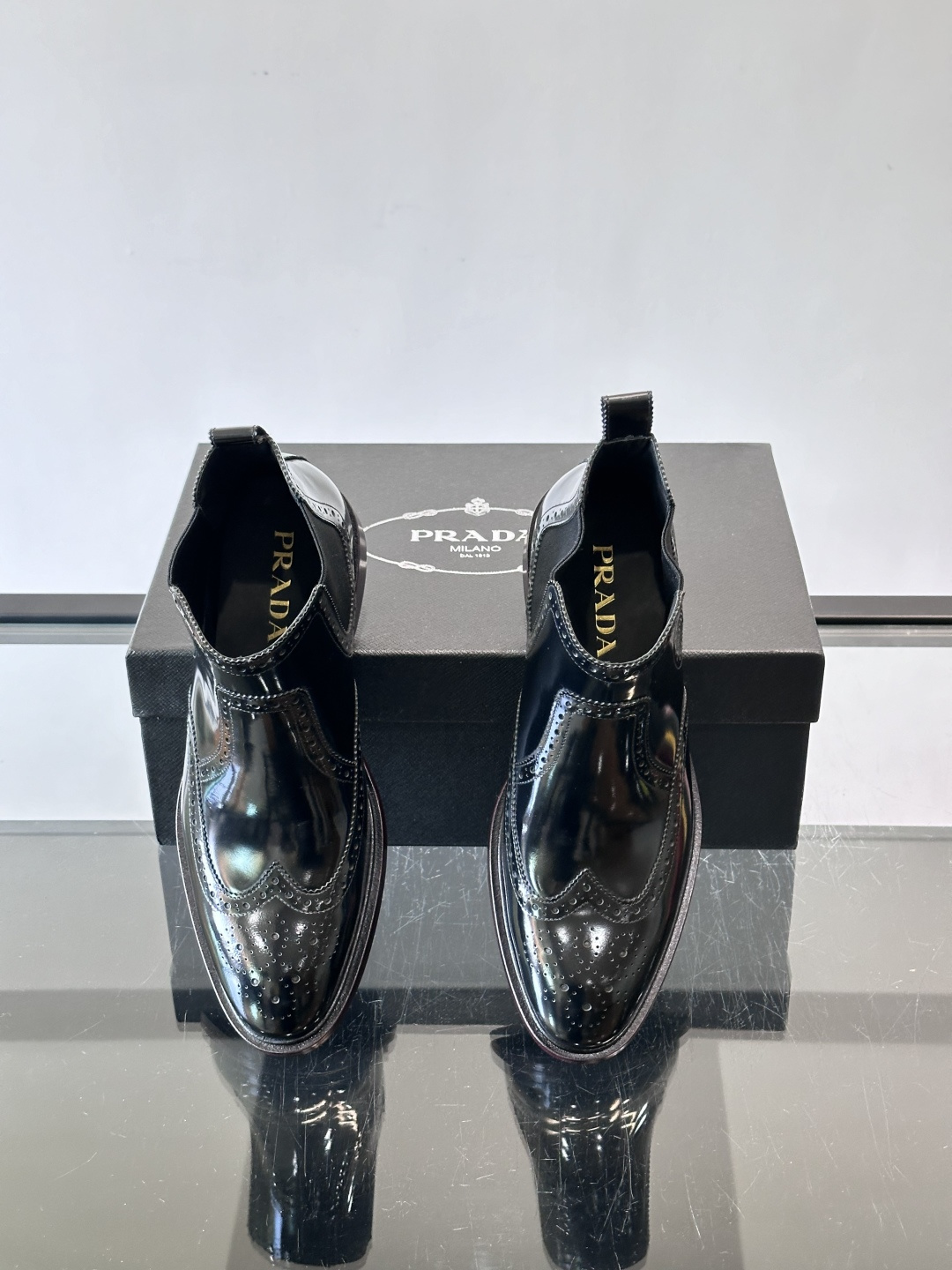 Prada普拉达布洛克雕花切尔西靴，英伦风代表，采用高光抛光皮革，光泽感如黑曜石。鞋面布洛克雕花，细节精