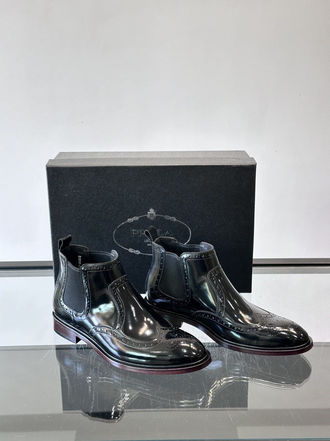Prada普拉达布洛克雕花切尔西靴，英伦风代表，采用高光抛光皮革，光泽感如黑曜石。鞋面布洛克雕花，细节精
