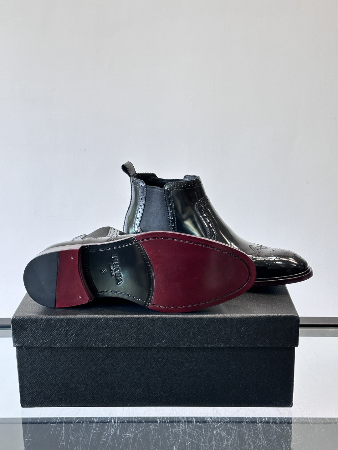 Prada普拉达布洛克雕花切尔西靴，英伦风代表，采用高光抛光皮革，光泽感如黑曜石。鞋面布洛克雕花，细节精