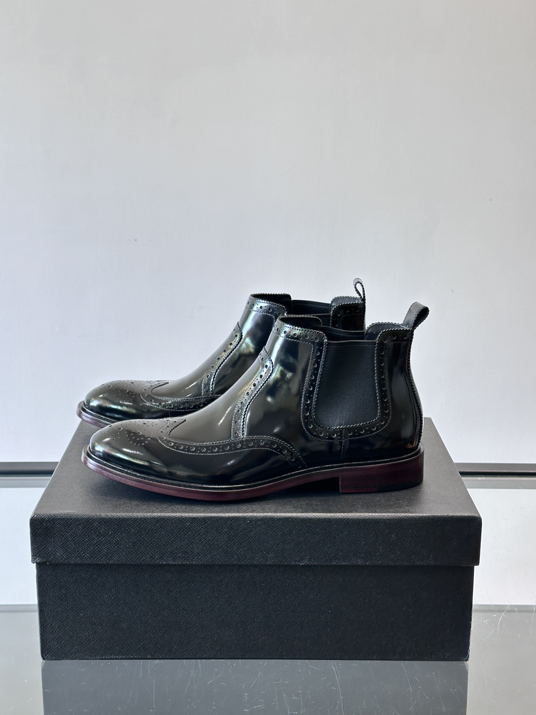 Prada普拉达布洛克雕花切尔西靴，英伦风代表，采用高光抛光皮革，光泽感如黑曜石。鞋面布洛克雕花，细节精