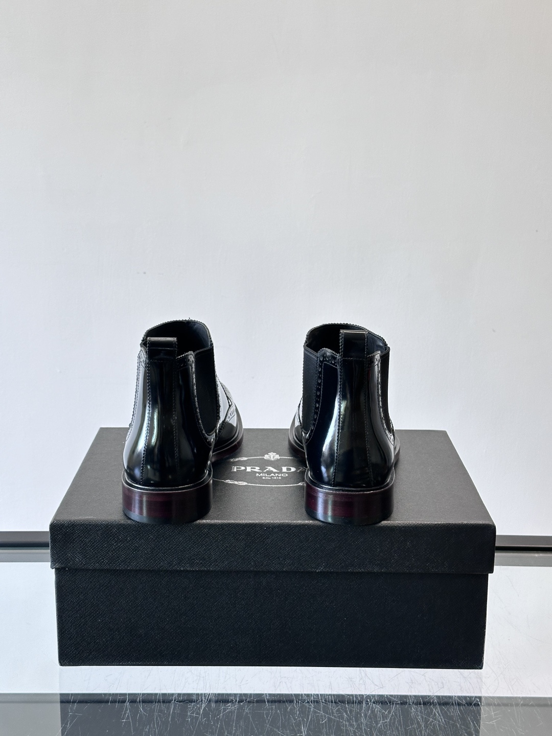 Prada普拉达布洛克雕花切尔西靴，英伦风代表，采用高光抛光皮革，光泽感如黑曜石。鞋面布洛克雕花，细节精