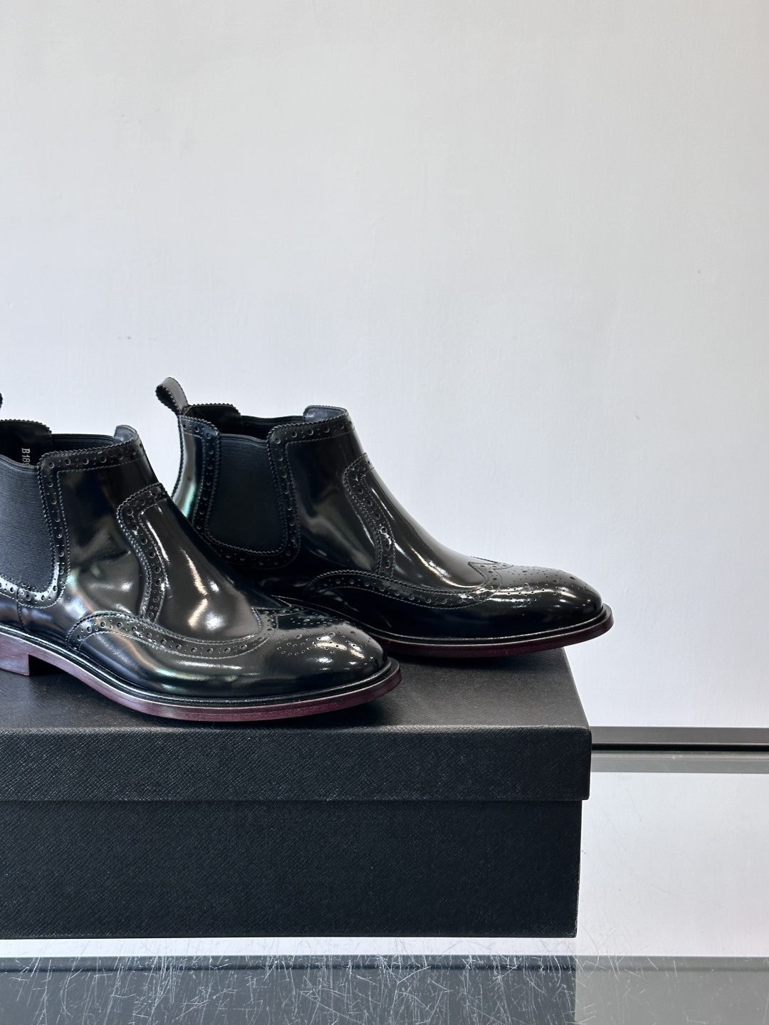 Prada普拉达布洛克雕花切尔西靴，英伦风代表，采用高光抛光皮革，光泽感如黑曜石。鞋面布洛克雕花，细节精