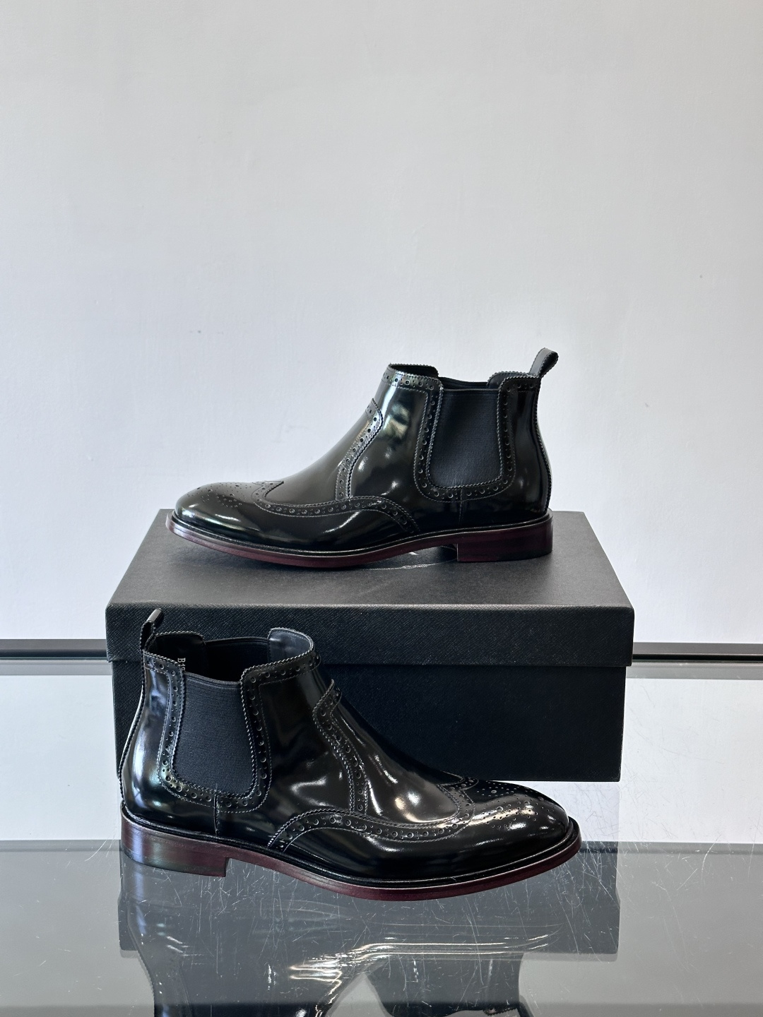 Prada普拉达布洛克雕花切尔西靴，英伦风代表，采用高光抛光皮革，光泽感如黑曜石。鞋面布洛克雕花，细节精