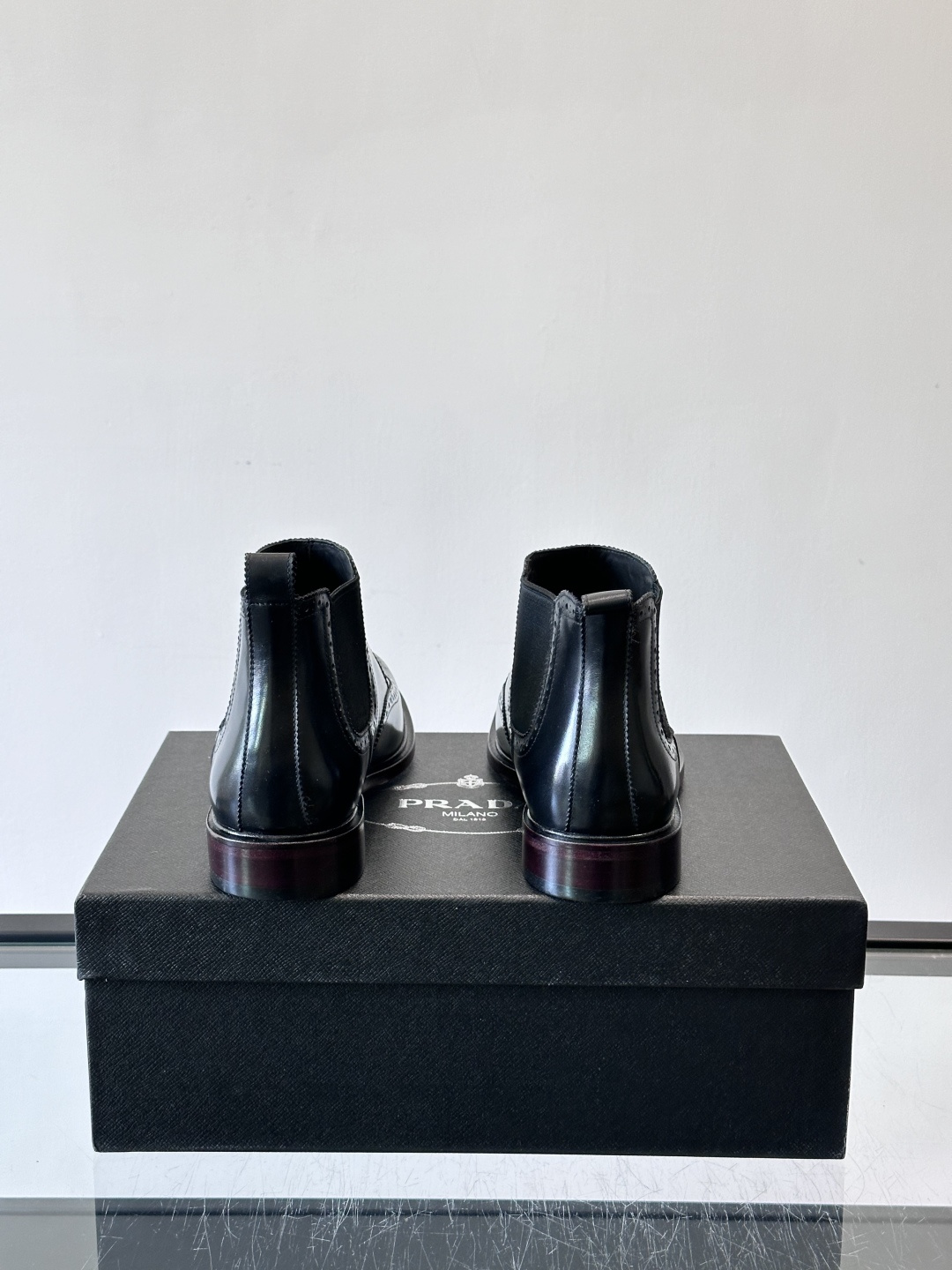 Prada普拉达布洛克雕花切尔西靴，英伦风代表，采用高光抛光皮革，光泽感如黑曜石。鞋面布洛克雕花，细节精