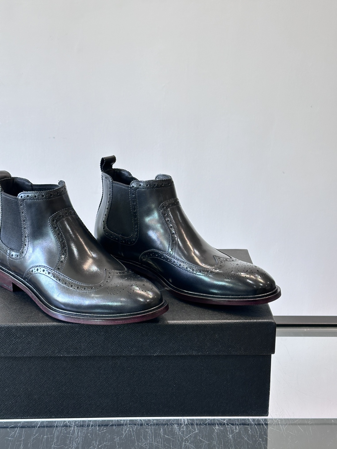 Prada普拉达布洛克雕花切尔西靴，英伦风代表，采用高光抛光皮革，光泽感如黑曜石。鞋面布洛克雕花，细节精