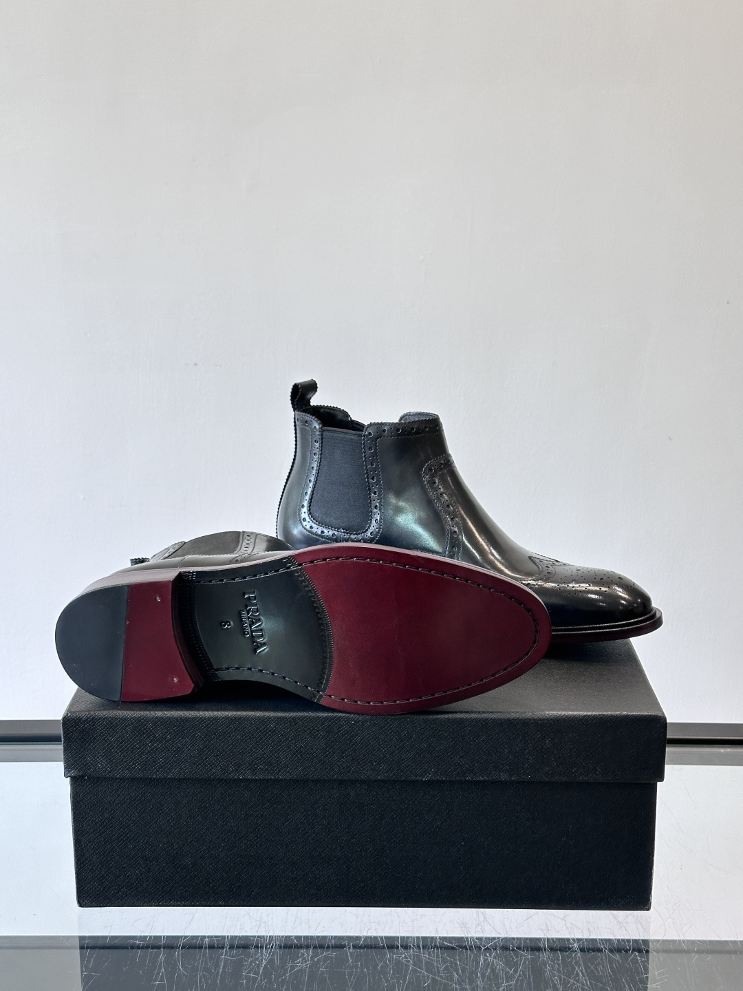 Prada普拉达布洛克雕花切尔西靴，英伦风代表，采用高光抛光皮革，光泽感如黑曜石。鞋面布洛克雕花，细节精