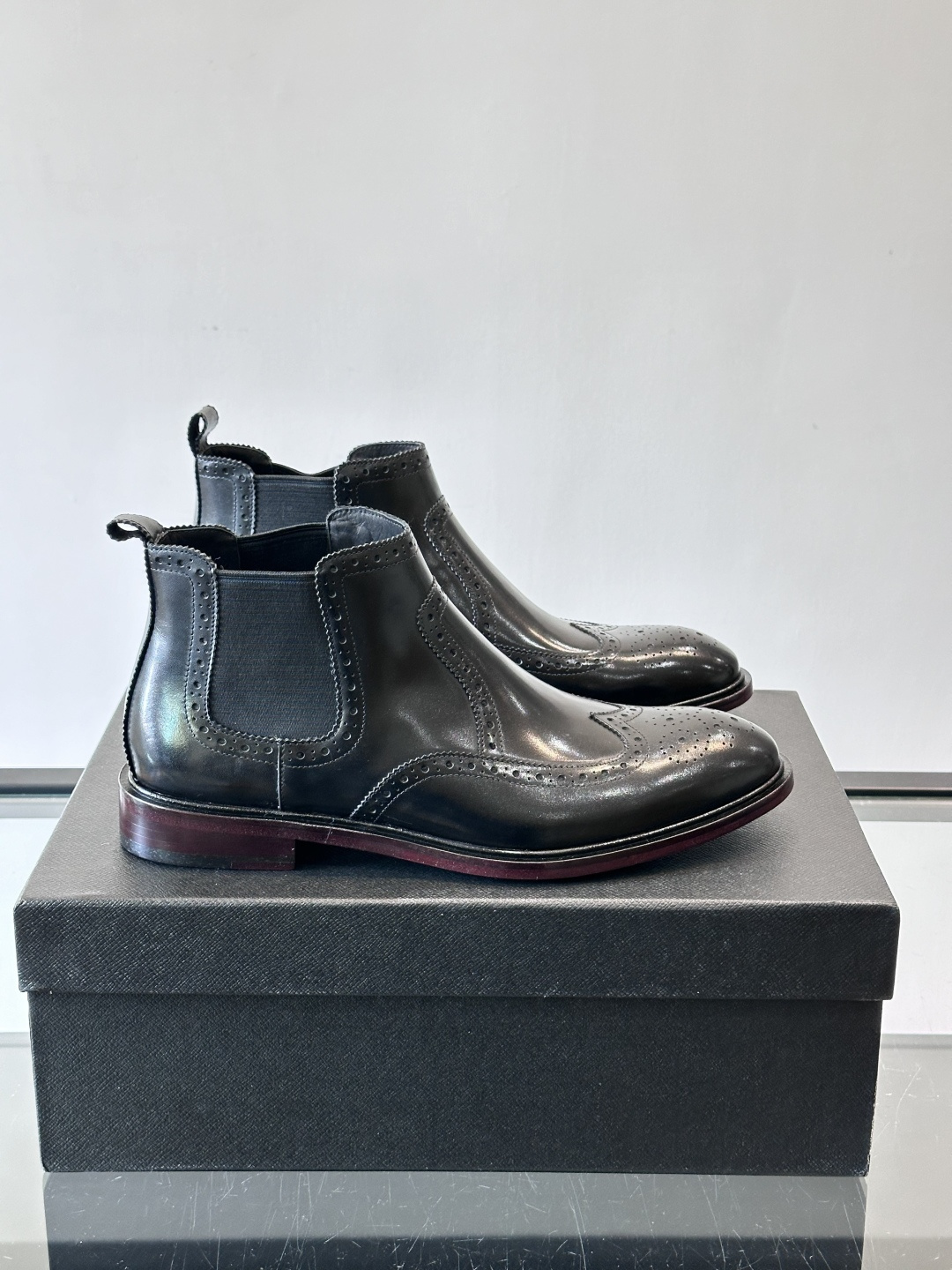 Prada普拉达布洛克雕花切尔西靴，英伦风代表，采用高光抛光皮革，光泽感如黑曜石。鞋面布洛克雕花，细节精