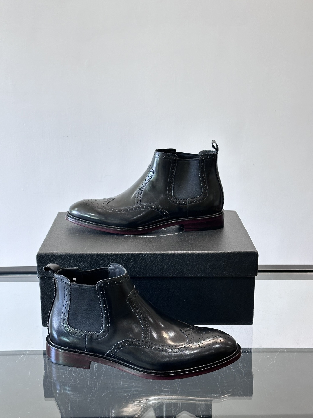 Prada普拉达布洛克雕花切尔西靴，英伦风代表，采用高光抛光皮革，光泽感如黑曜石。鞋面布洛克雕花，细节精