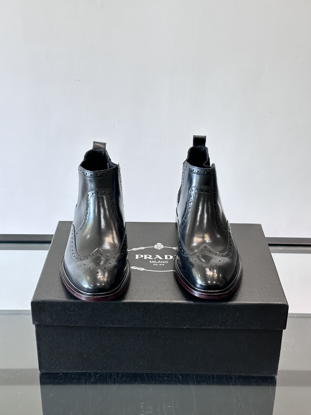 Prada普拉达布洛克雕花切尔西靴，英伦风代表，采用高光抛光皮革，光泽感如黑曜石。鞋面布洛克雕花，细节精