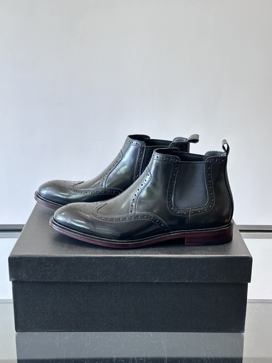 Prada普拉达布洛克雕花切尔西靴，英伦风代表，采用高光抛光皮革，光泽感如黑曜石。鞋面布洛克雕花，细节精