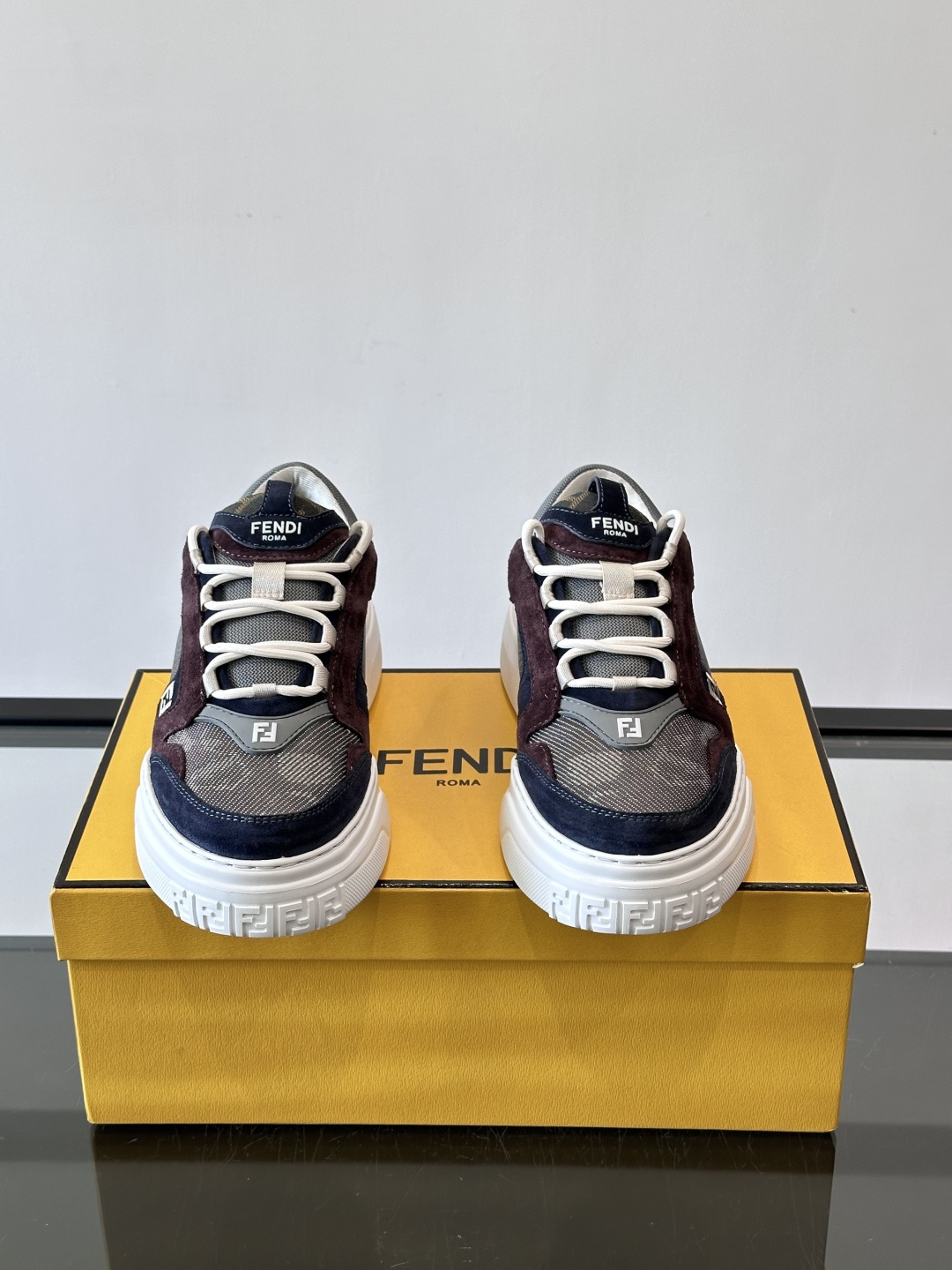 FENDI男士老爹鞋采用深紫、藏蓝与灰色拼接设计，麂皮与网眼材质混搭，厚底白色中底印有品牌Logo，整体