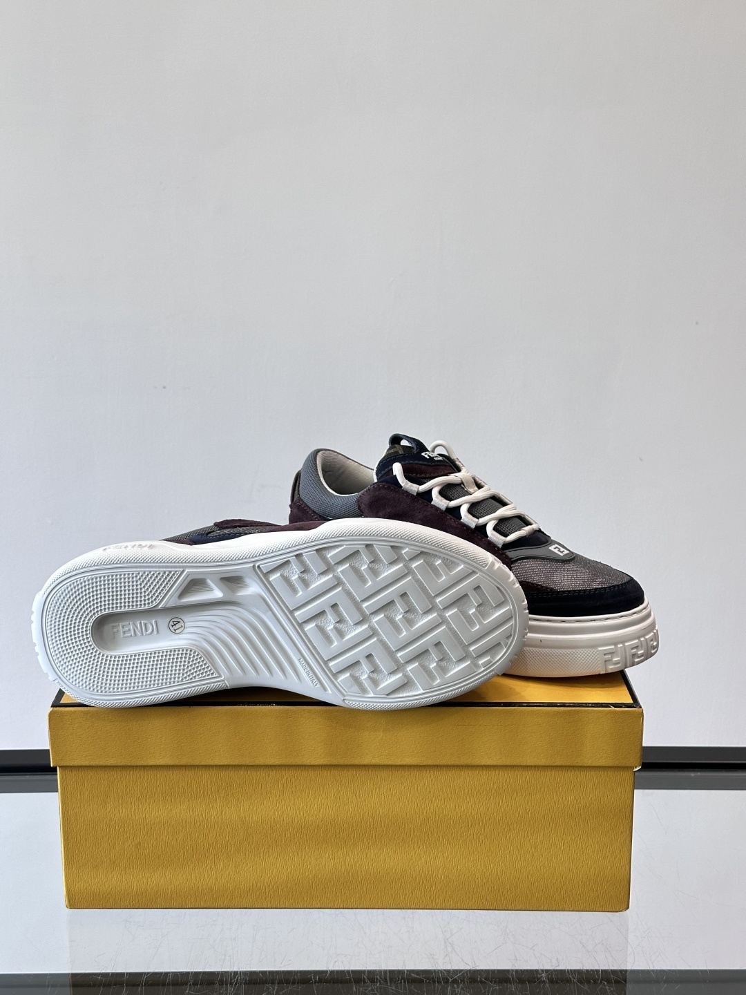 FENDI男士老爹鞋采用深紫、藏蓝与灰色拼接设计，麂皮与网眼材质混搭，厚底白色中底印有品牌Logo，整体