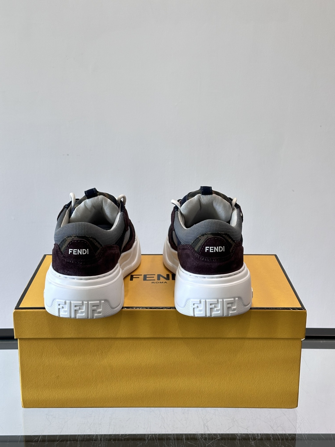 FENDI男士老爹鞋采用深紫、藏蓝与灰色拼接设计，麂皮与网眼材质混搭，厚底白色中底印有品牌Logo，整体