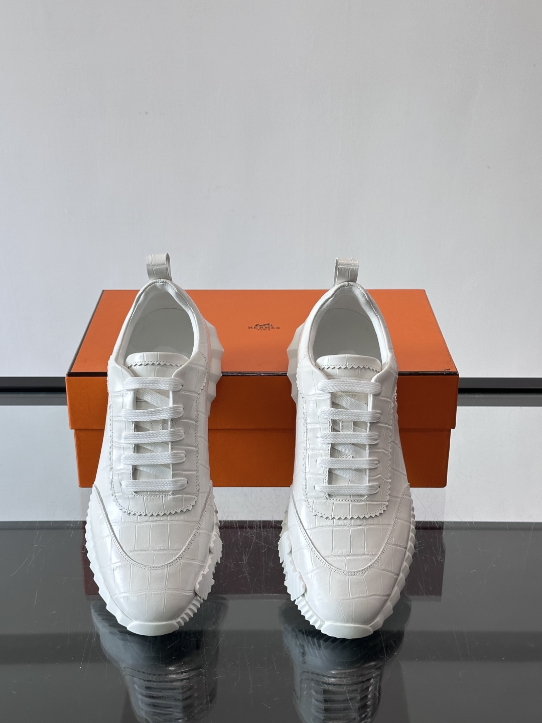 H爱马仕这双鞋是经典的鳄鱼纹运动鞋，鞋面采用仿鳄鱼皮纹理设计，搭配标志性的锯齿状厚底，整体风格兼具奢华感