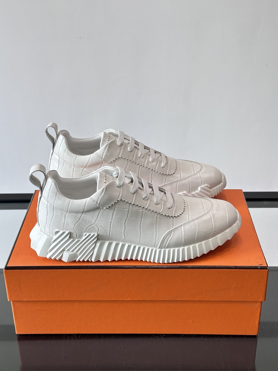 H爱马仕这双鞋是经典的鳄鱼纹运动鞋，鞋面采用仿鳄鱼皮纹理设计，搭配标志性的锯齿状厚底，整体风格兼具奢华感