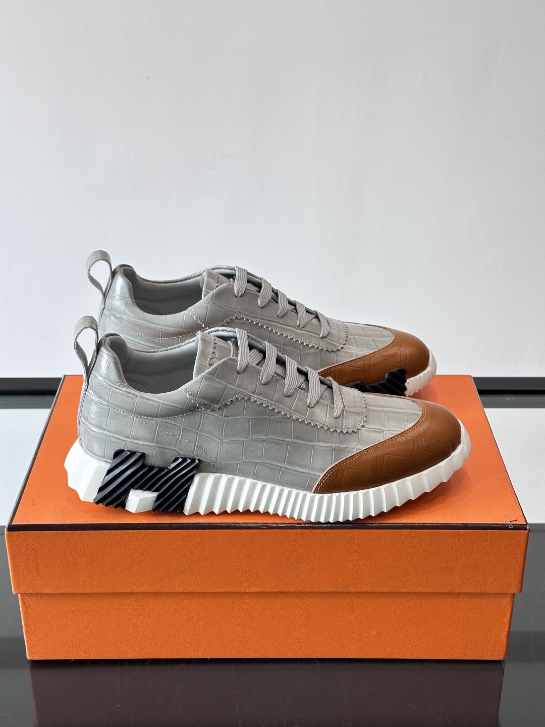 H爱马仕这双鞋是经典的鳄鱼纹运动鞋，鞋面采用仿鳄鱼皮纹理设计，搭配标志性的锯齿状厚底，整体风格兼具奢华感