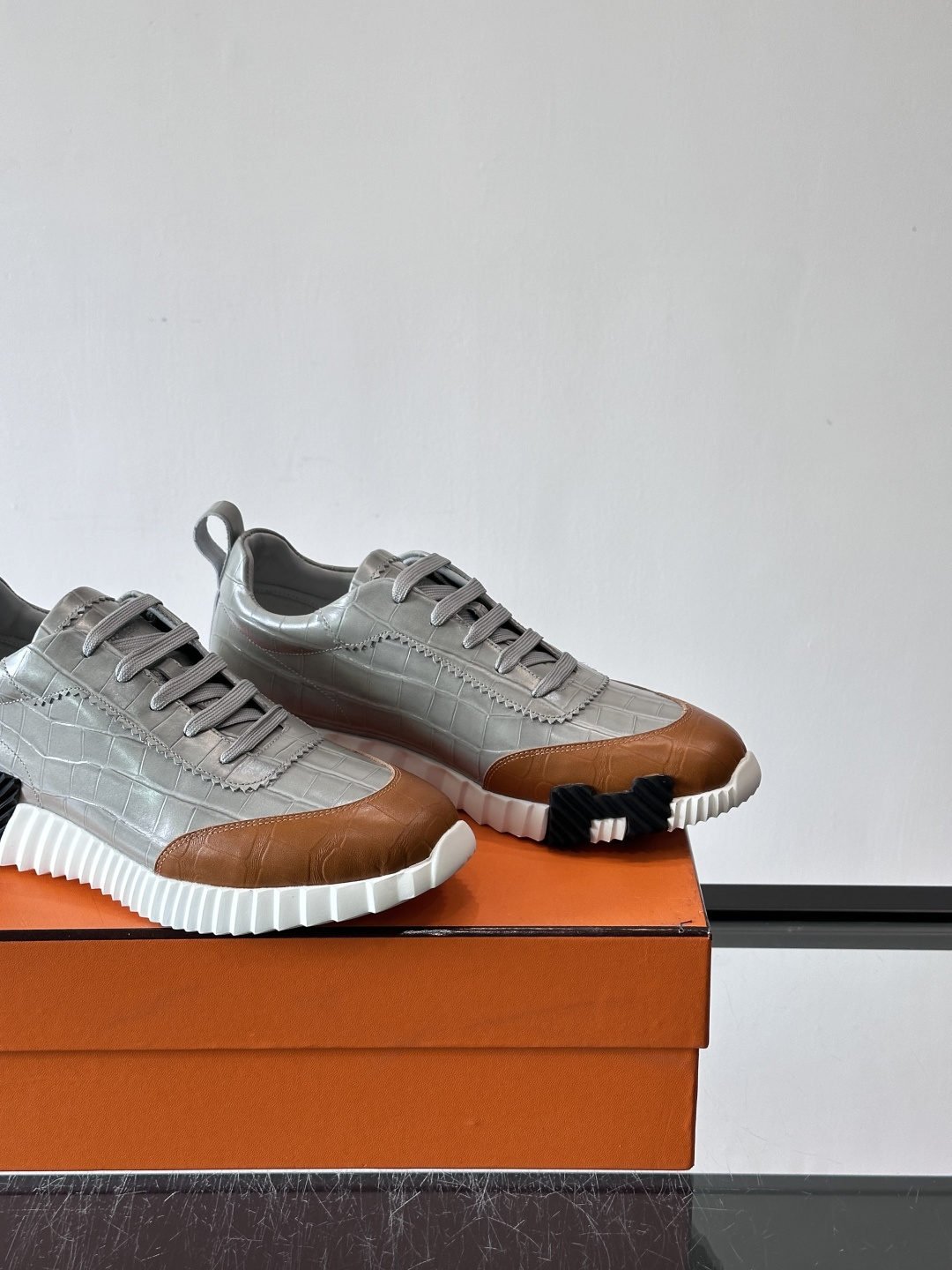H爱马仕这双鞋是经典的鳄鱼纹运动鞋，鞋面采用仿鳄鱼皮纹理设计，搭配标志性的锯齿状厚底，整体风格兼具奢华感