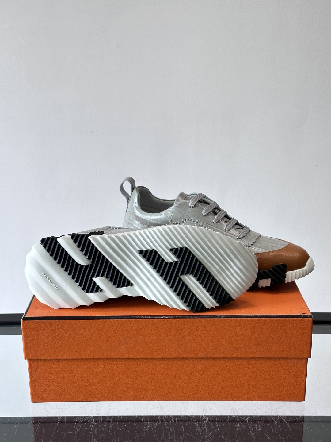 H爱马仕这双鞋是经典的鳄鱼纹运动鞋，鞋面采用仿鳄鱼皮纹理设计，搭配标志性的锯齿状厚底，整体风格兼具奢华感