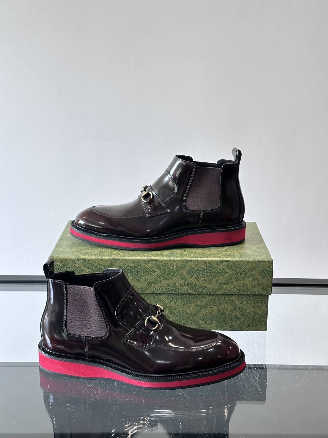 Gucci经典的拼色切尔西靴，采用高光泽黑色皮革搭配标志性的红绿织带细节，鞋底为亮眼的红色，整体设计兼具