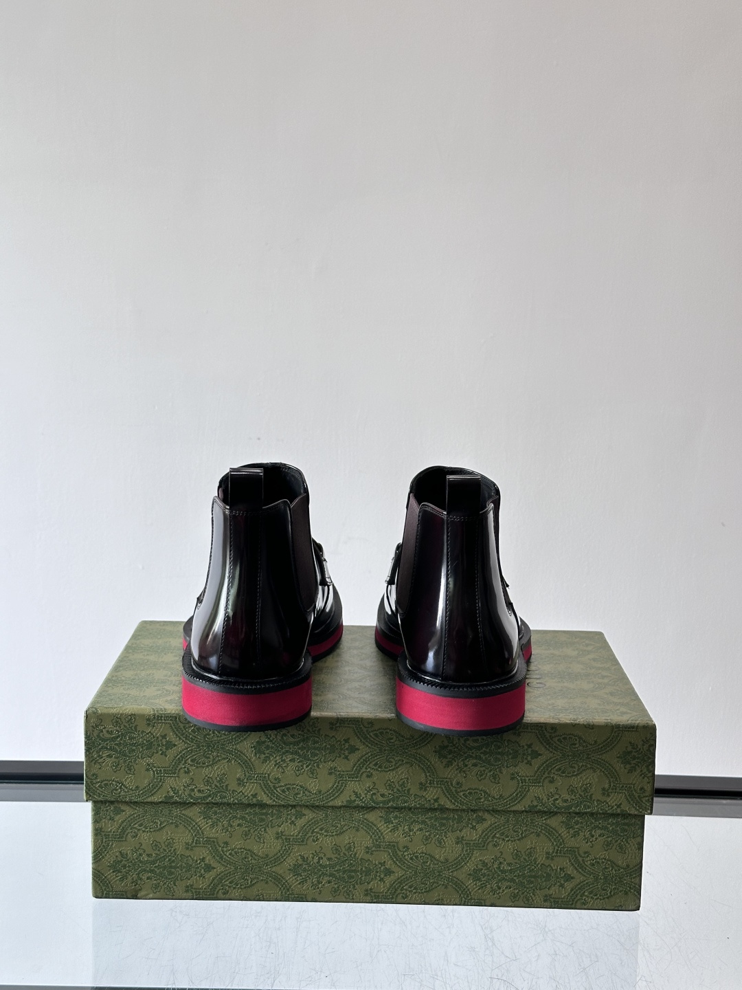 Gucci经典的拼色切尔西靴，采用高光泽黑色皮革搭配标志性的红绿织带细节，鞋底为亮眼的红色，整体设计兼具