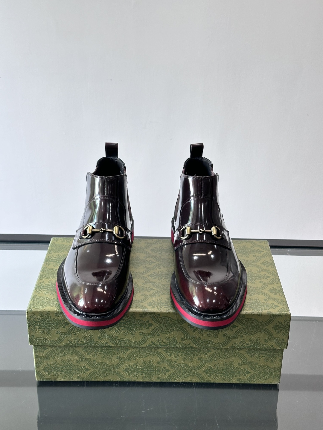 Gucci经典的拼色切尔西靴，采用高光泽黑色皮革搭配标志性的红绿织带细节，鞋底为亮眼的红色，整体设计兼具