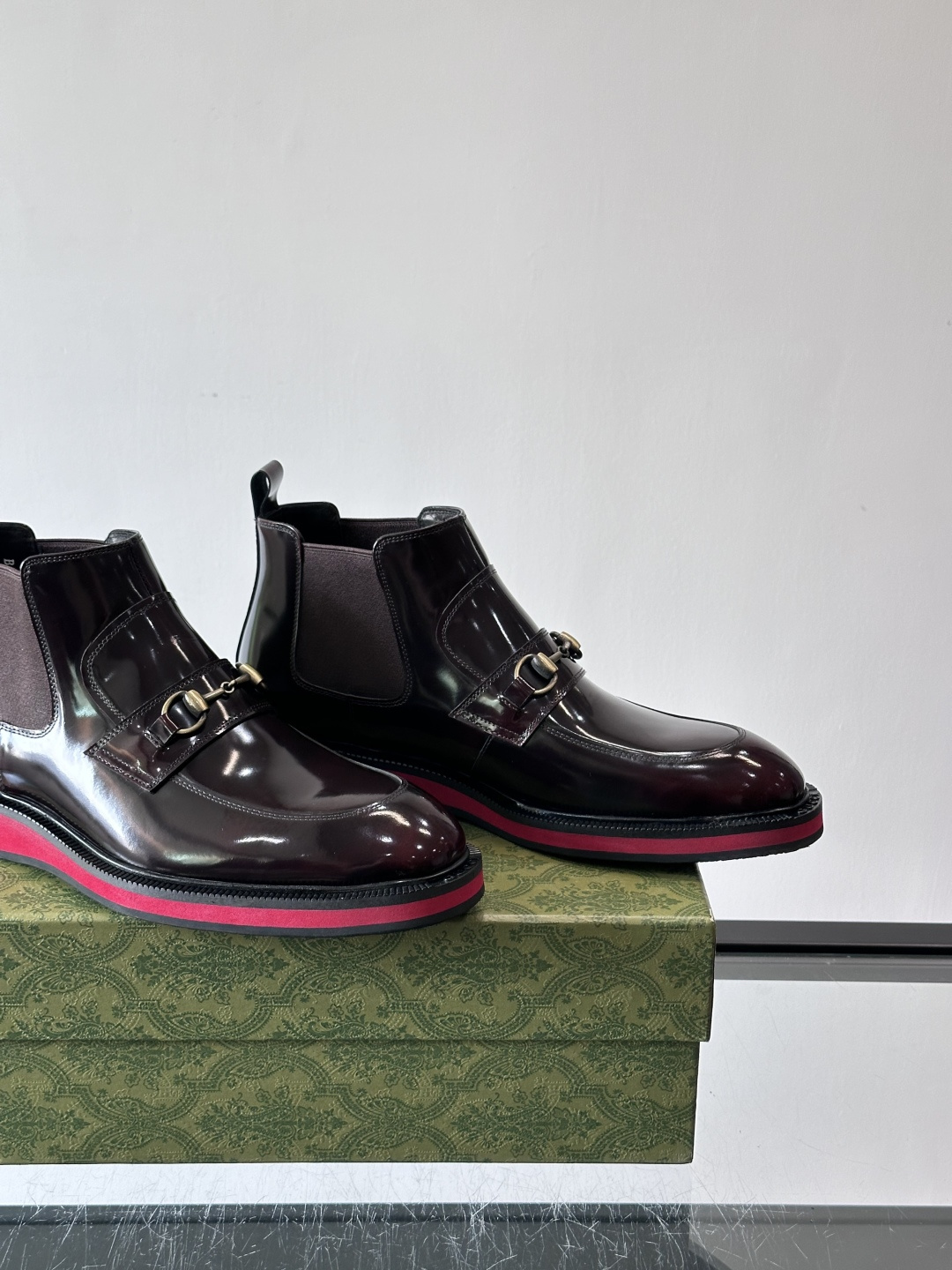 Gucci经典的拼色切尔西靴，采用高光泽黑色皮革搭配标志性的红绿织带细节，鞋底为亮眼的红色，整体设计兼具