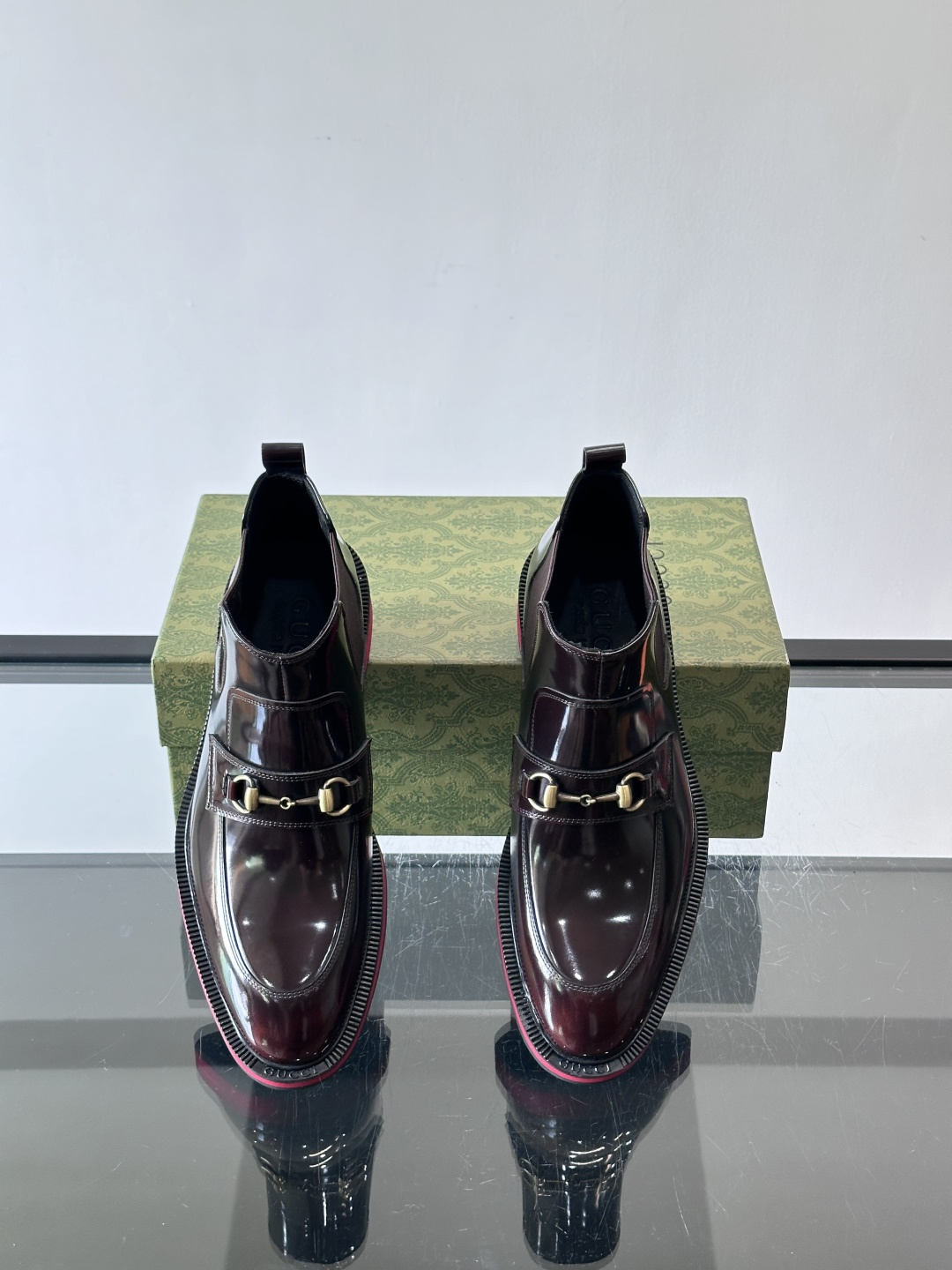 Gucci经典的拼色切尔西靴，采用高光泽黑色皮革搭配标志性的红绿织带细节，鞋底为亮眼的红色，整体设计兼具