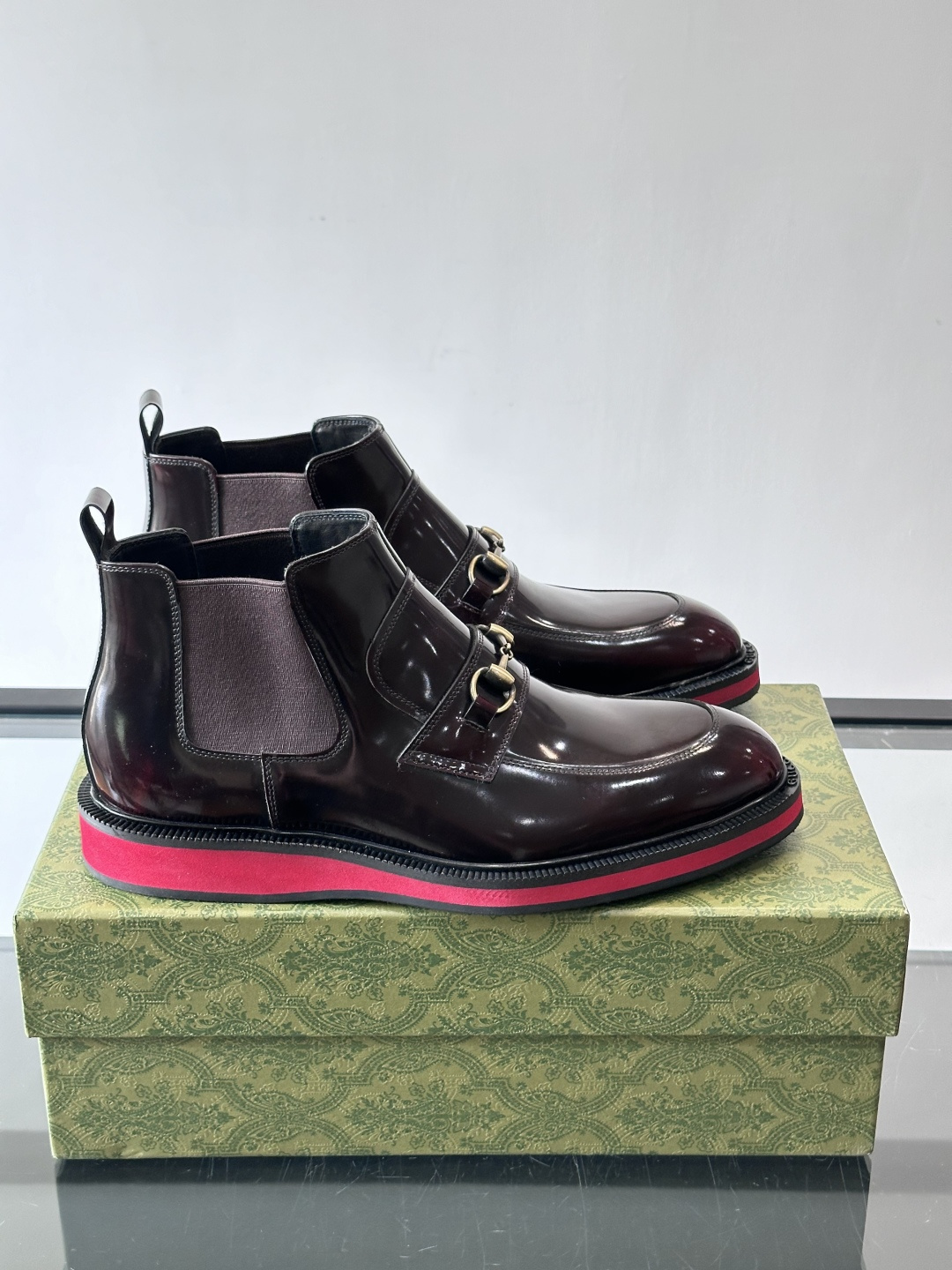 Gucci经典的拼色切尔西靴，采用高光泽黑色皮革搭配标志性的红绿织带细节，鞋底为亮眼的红色，整体设计兼具