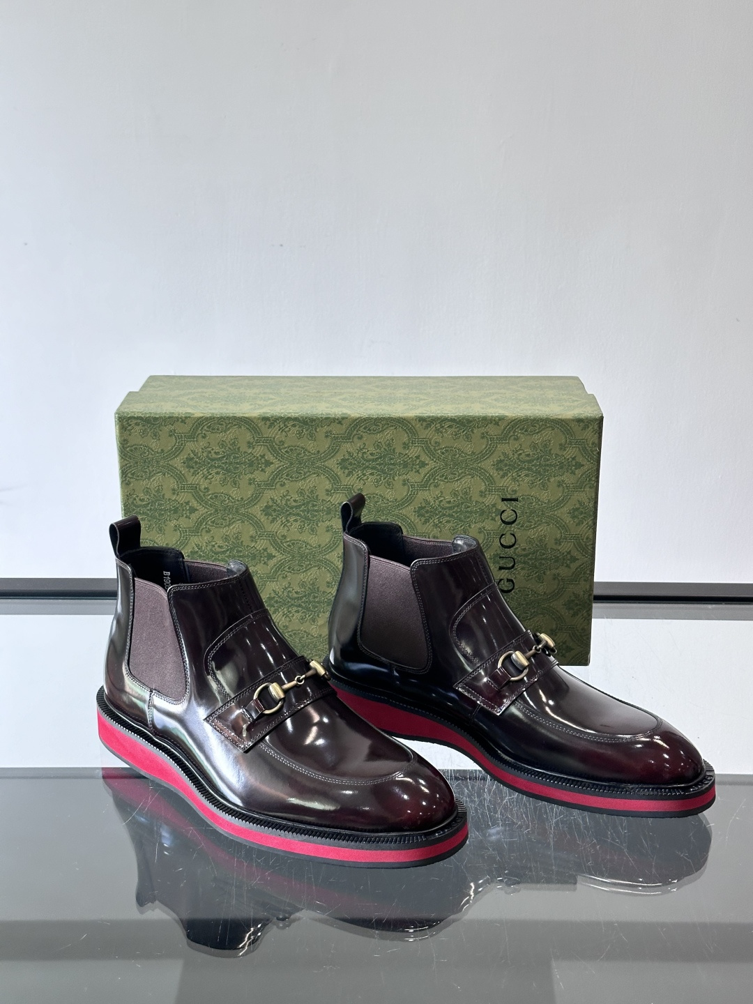 Gucci经典的拼色切尔西靴，采用高光泽黑色皮革搭配标志性的红绿织带细节，鞋底为亮眼的红色，整体设计兼具
