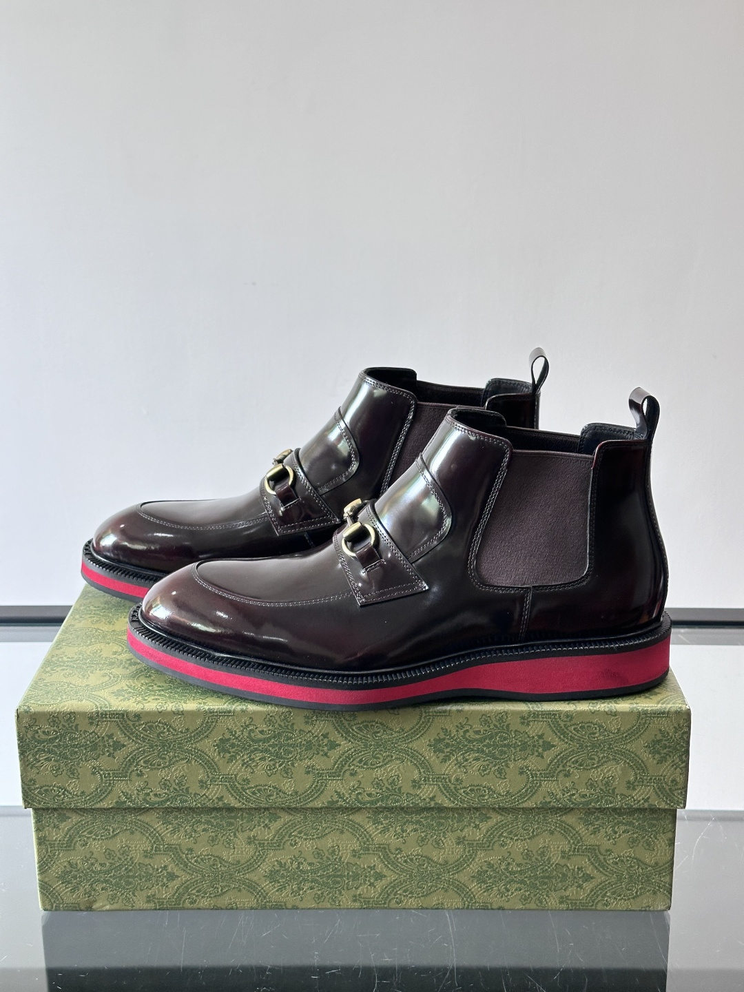 Gucci经典的拼色切尔西靴，采用高光泽黑色皮革搭配标志性的红绿织带细节，鞋底为亮眼的红色，整体设计兼具