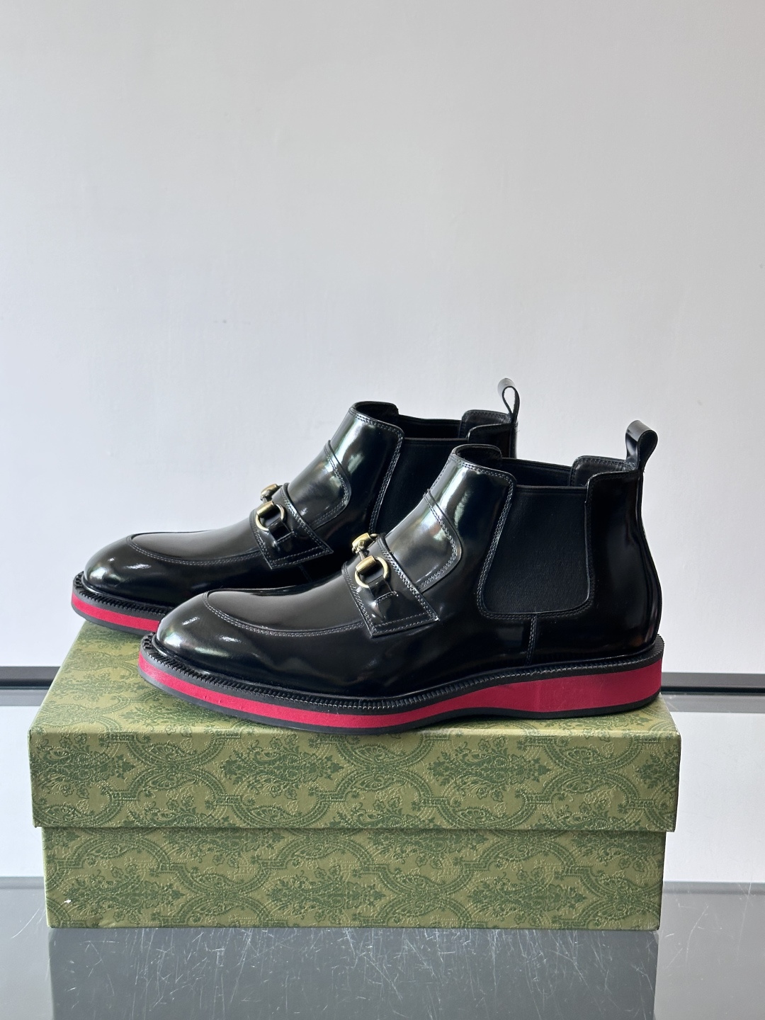 Gucci经典的拼色切尔西靴，采用高光泽黑色皮革搭配标志性的红绿织带细节，鞋底为亮眼的红色，整体设计兼具