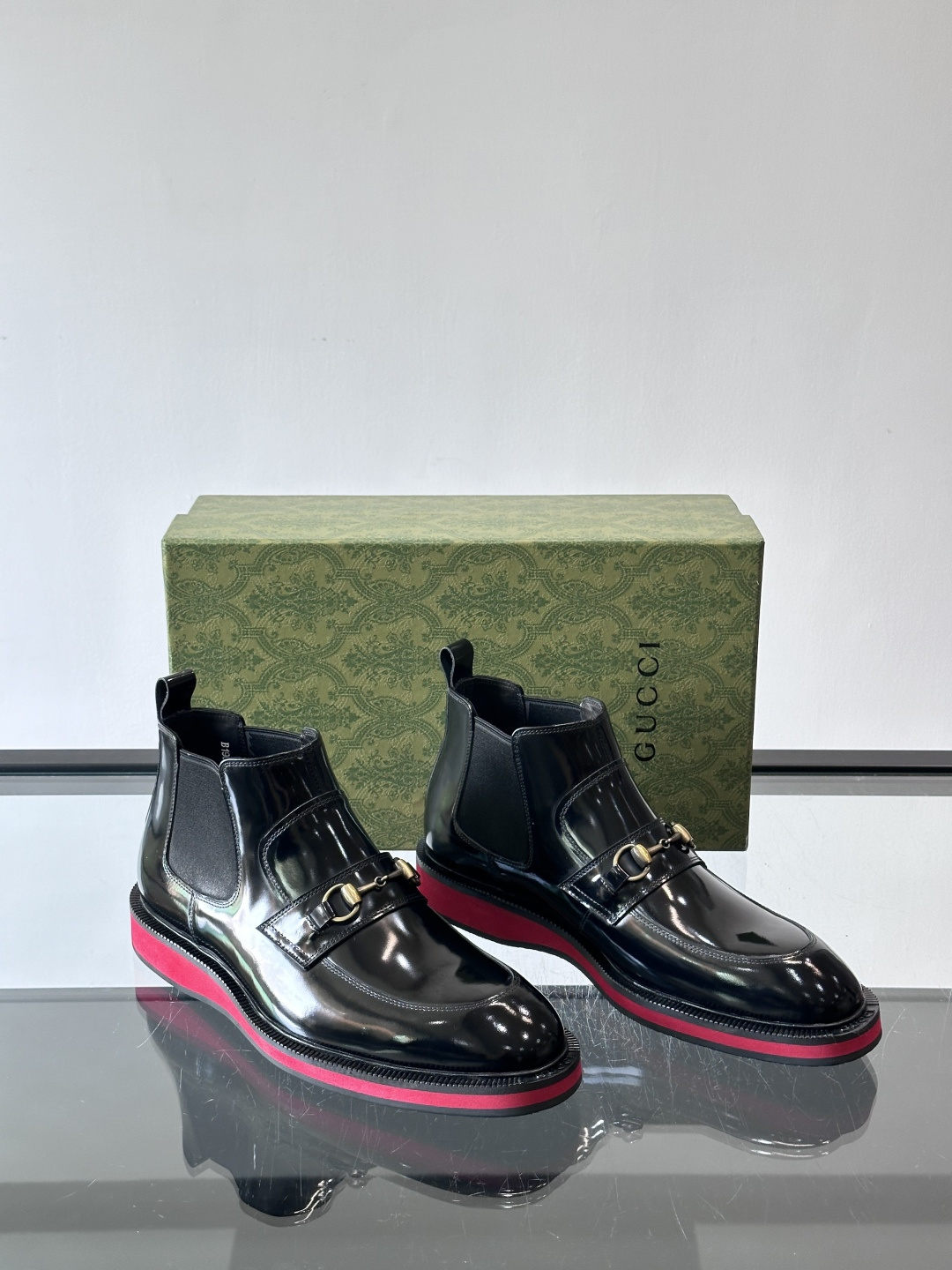 Gucci经典的拼色切尔西靴，采用高光泽黑色皮革搭配标志性的红绿织带细节，鞋底为亮眼的红色，整体设计兼具