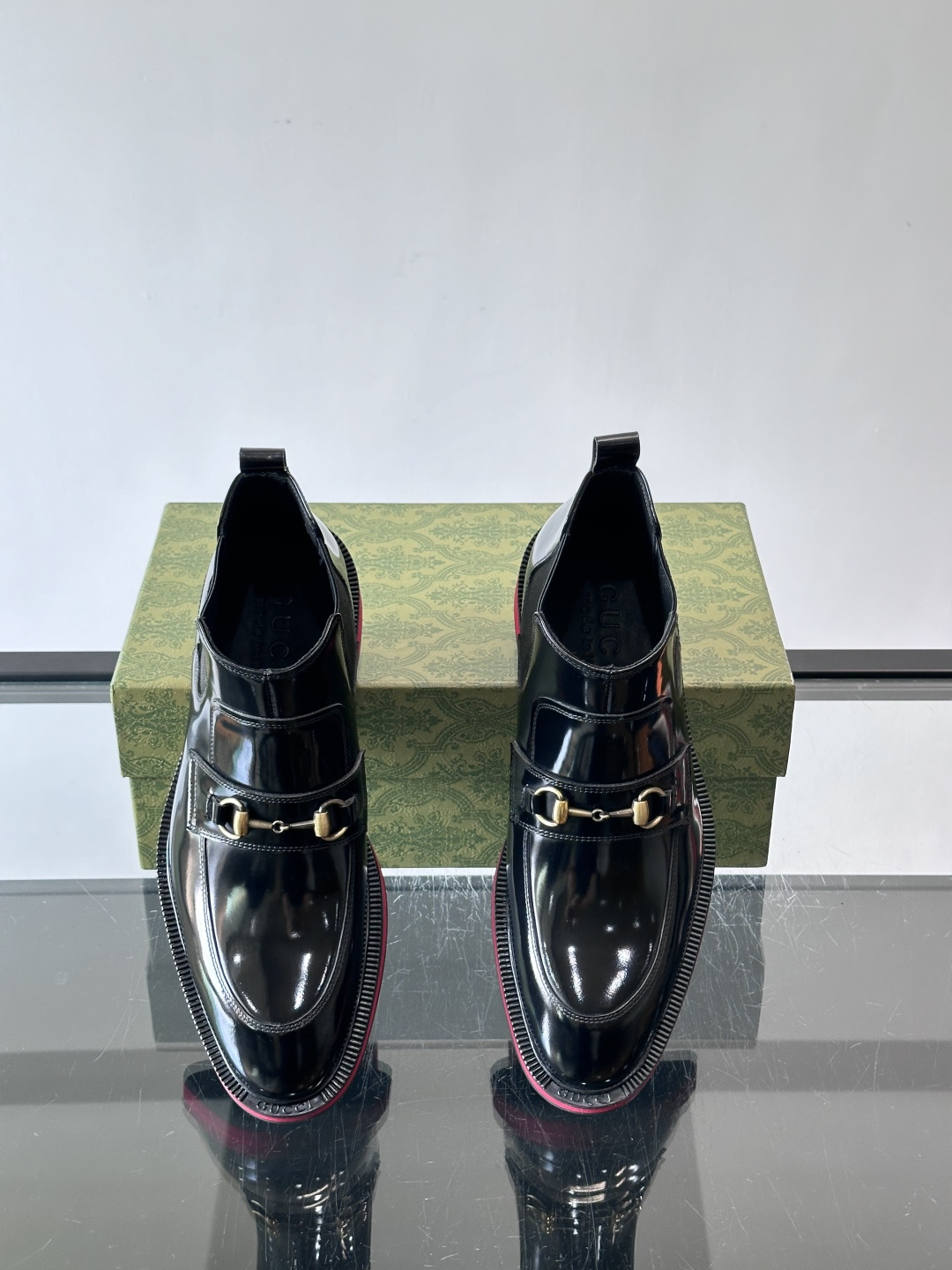 Gucci经典的拼色切尔西靴，采用高光泽黑色皮革搭配标志性的红绿织带细节，鞋底为亮眼的红色，整体设计兼具