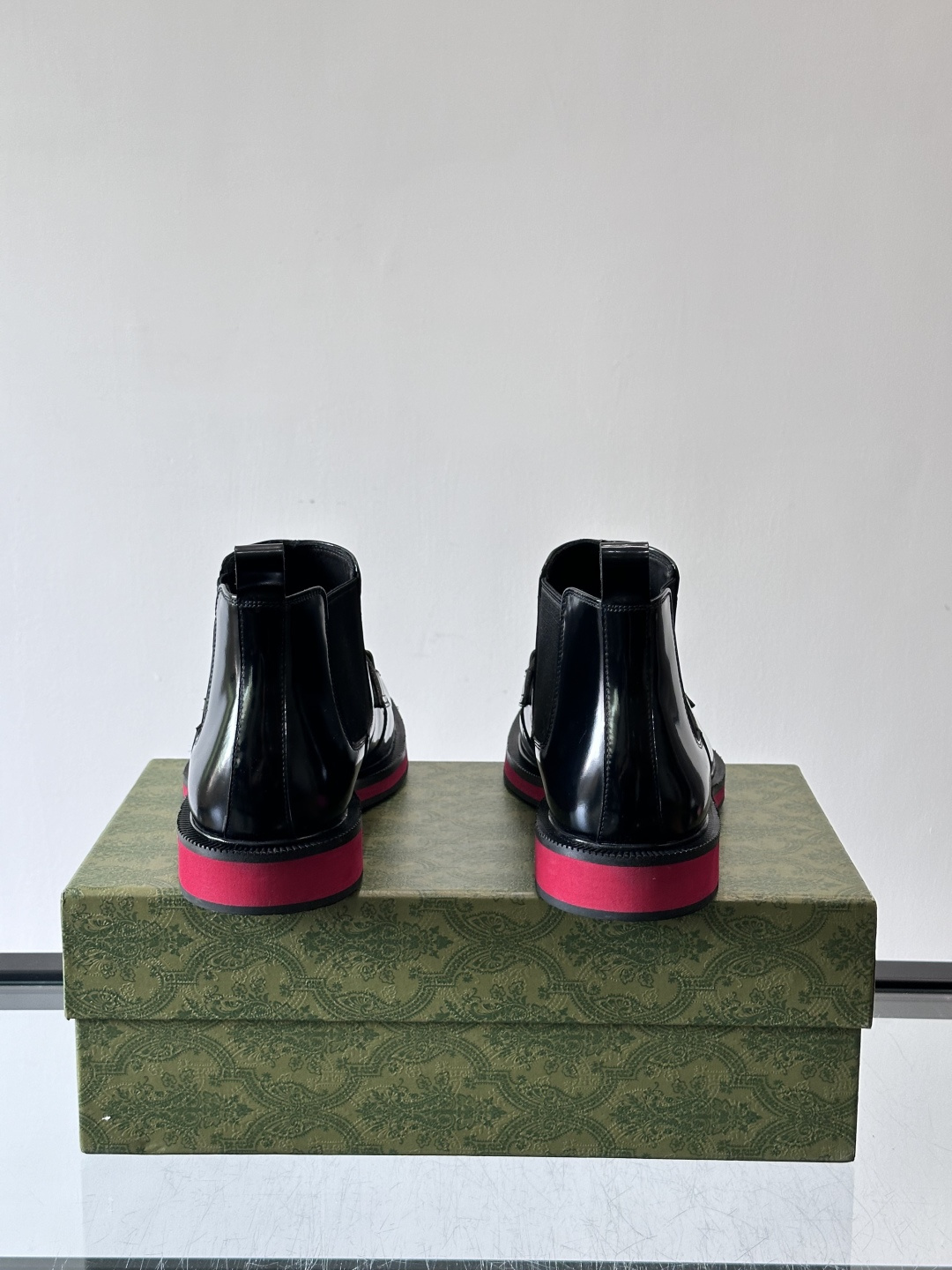 Gucci经典的拼色切尔西靴，采用高光泽黑色皮革搭配标志性的红绿织带细节，鞋底为亮眼的红色，整体设计兼具