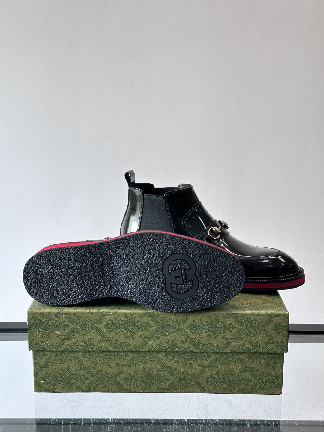 Gucci经典的拼色切尔西靴，采用高光泽黑色皮革搭配标志性的红绿织带细节，鞋底为亮眼的红色，整体设计兼具