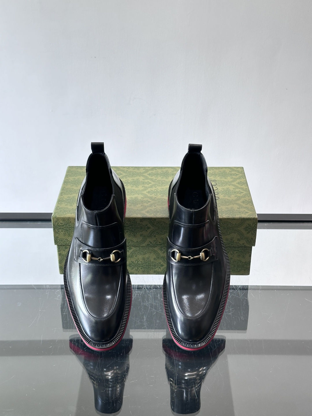 Gucci经典的拼色切尔西靴，采用高光泽黑色皮革搭配标志性的红绿织带细节，鞋底为亮眼的红色，整体设计兼具